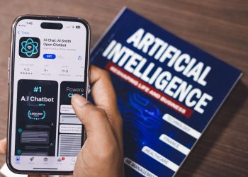 Smartphone displaying AI app with book on AI technology in background.