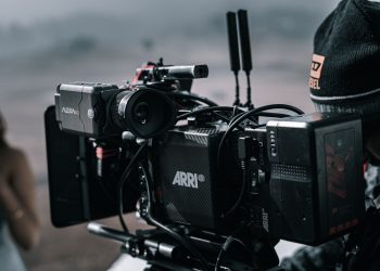 Close-up of a professional filmmaking camera setup on an outdoor set with blurred background.