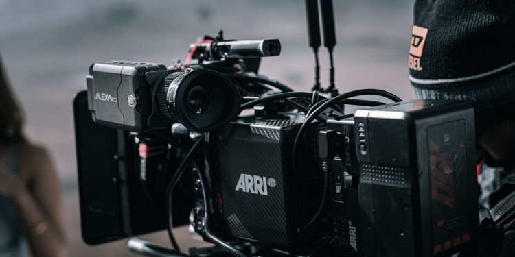 Close-up of a professional filmmaking camera setup on an outdoor set with blurred background.
