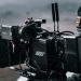 Close-up of a professional filmmaking camera setup on an outdoor set with blurred background.