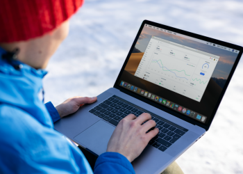 Person working on a laptop analyzing charts in an outdoor setting during winter.