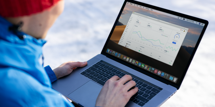 Person working on a laptop analyzing charts in an outdoor setting during winter.