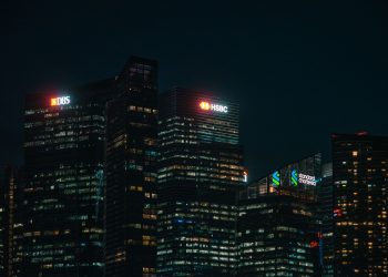 Illuminated city skyscrapers of major banks in Singapore's financial district at night.