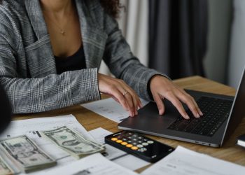 A businesswoman working on finance management with cash and calculator on desk.
