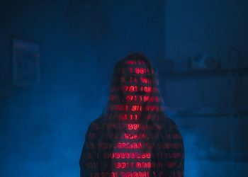 A mysterious silhouette with red binary code projected over the face, set against a dark, moody background.