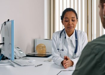 A female doctor consulting a patient in a modern medical office setting.