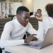 Young man intently working on a laptop in an office setting, concentrating on his task.