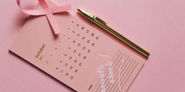 Pink calendar with ribbon and pen for Breast Cancer Awareness in October.