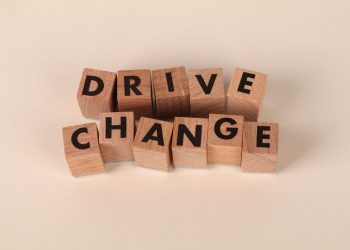 Wooden blocks spelling 'Drive Change' on a neutral background, symbolizing motivation and growth.