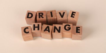 Wooden blocks spelling 'Drive Change' on a neutral background, symbolizing motivation and growth.