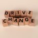 Wooden blocks spelling 'Drive Change' on a neutral background, symbolizing motivation and growth.