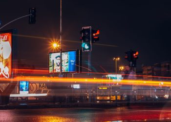 A vibrant city street scene captured at night with long exposure showing traffic lights and light trails.