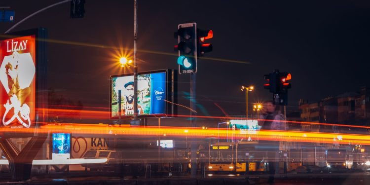 A vibrant city street scene captured at night with long exposure showing traffic lights and light trails.