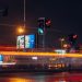 A vibrant city street scene captured at night with long exposure showing traffic lights and light trails.
