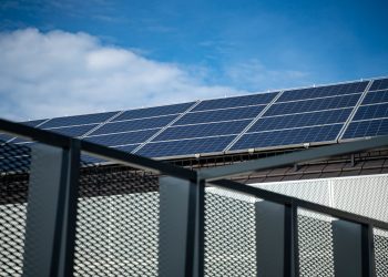Close-up view of modern solar panels on a rooftop against a clear blue sky, representing clean energy.
