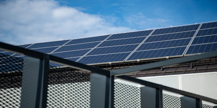 Close-up view of modern solar panels on a rooftop against a clear blue sky, representing clean energy.