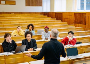 Professor teaching a diverse group of students in a university lecture hall.