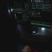 Dark room setup with code displayed on PC monitors highlighting cybersecurity themes.