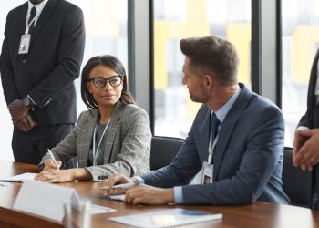 Diverse business professionals discussing strategy during a modern board meeting.