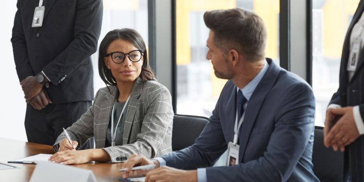 Diverse business professionals discussing strategy during a modern board meeting.