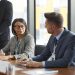 Diverse business professionals discussing strategy during a modern board meeting.
