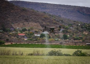 High-tech drone spraying crops for precision agriculture in a rural setting.