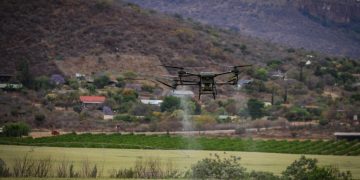 High-tech drone spraying crops for precision agriculture in a rural setting.