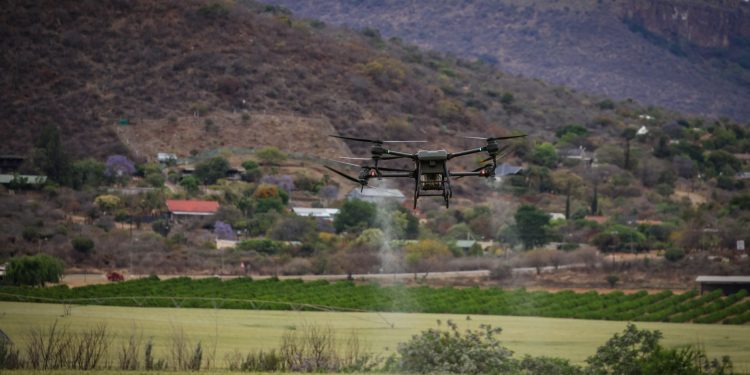 High-tech drone spraying crops for precision agriculture in a rural setting.