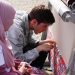 Detailed view of artisans weaving a traditional carpet outdoors, showcasing craftsmanship and cultural heritage.