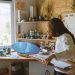 Woman artist painting a blue ocean scene on a skateboard in a cozy art studio.