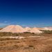 Scenic view of Australian desert showcasing mine dumps under clear blue sky.