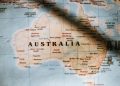 Closeup of political map of Australia with cities and regions with borders surrounded by seas and oceans placed on wall in sunny room