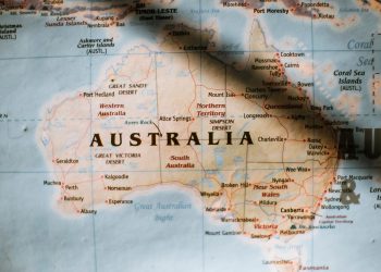 Closeup of political map of Australia with cities and regions with borders surrounded by seas and oceans placed on wall in sunny room