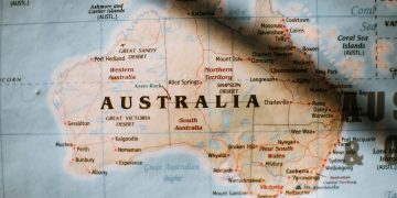 Closeup of political map of Australia with cities and regions with borders surrounded by seas and oceans placed on wall in sunny room