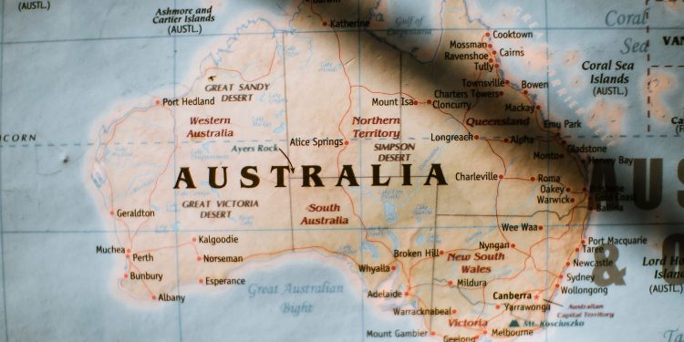 Closeup of political map of Australia with cities and regions with borders surrounded by seas and oceans placed on wall in sunny room