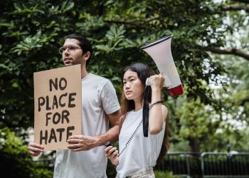Two diverse protesters holding a sign and megaphone in a peaceful outdoor demonstration.