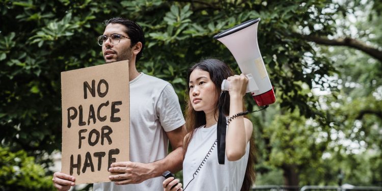 Two diverse protesters holding a sign and megaphone in a peaceful outdoor demonstration.