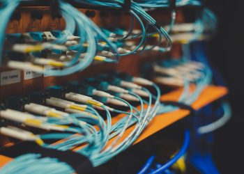 Closeup of many cables with blue wires plugged in modern switch with similar adapters on blurred background in modern studio
