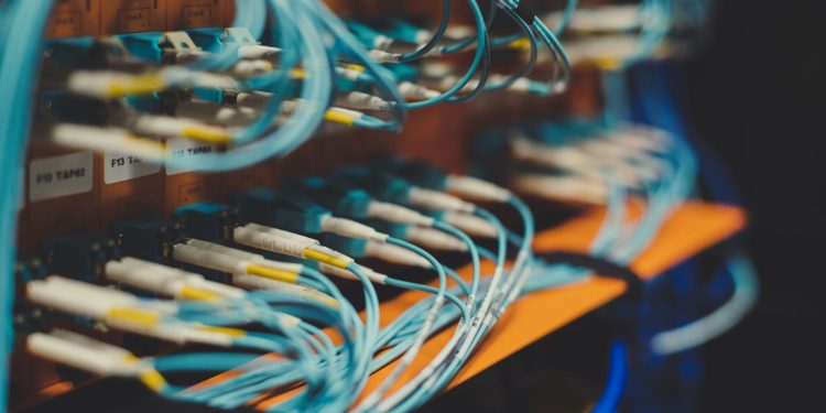 Closeup of many cables with blue wires plugged in modern switch with similar adapters on blurred background in modern studio