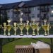 Lineup of gold trophies on a table outdoors with apartment backdrop.