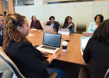 A diverse group of professionals working together in a modern conference room with laptops.