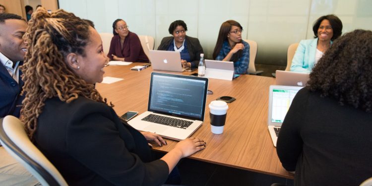 A diverse group of professionals working together in a modern conference room with laptops.