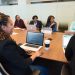 A diverse group of professionals working together in a modern conference room with laptops.