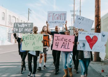Group of activists hold signs advocating for justice and equality during a street protest.