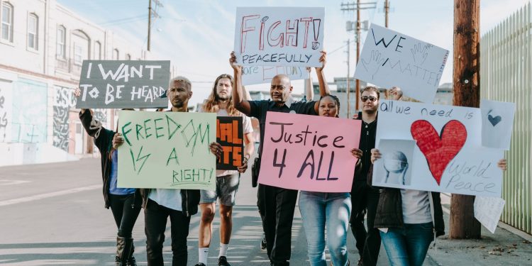 Group of activists hold signs advocating for justice and equality during a street protest.