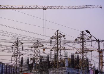 Construction site with cranes and power lines in Mumbai during evening hours.
