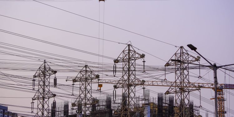 Construction site with cranes and power lines in Mumbai during evening hours.