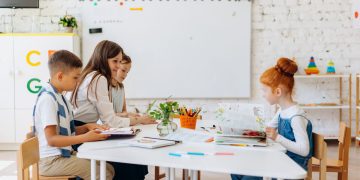 Students and teacher interacting in a bright, colorful classroom setting.