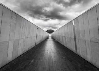 Symmetrical walkway in Canberra with dramatic clouds and modern architecture.