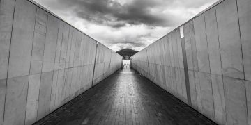Symmetrical walkway in Canberra with dramatic clouds and modern architecture.